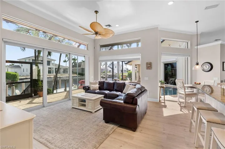 Living room featuring light wood-type flooring, ornamental molding, ceiling fan, and a wealth of natural light