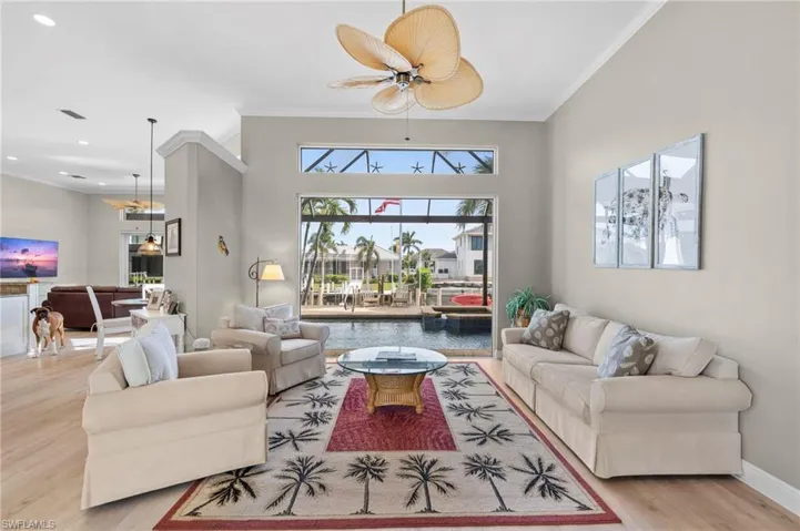 Living room with ornamental molding, ceiling fan, and light hardwood / wood-style flooring