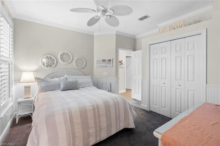 Carpeted bedroom with crown molding, ceiling fan, and a closet