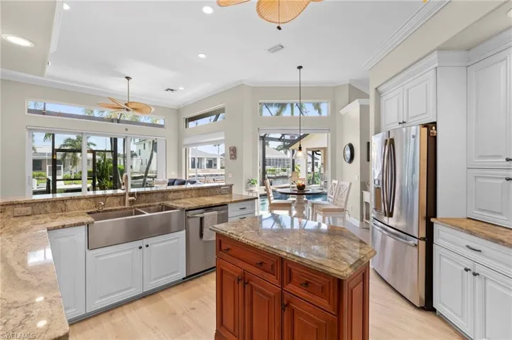 Kitchen featuring light stone countertops, stainless steel appliances, a wealth of natural light, and white cabinetry