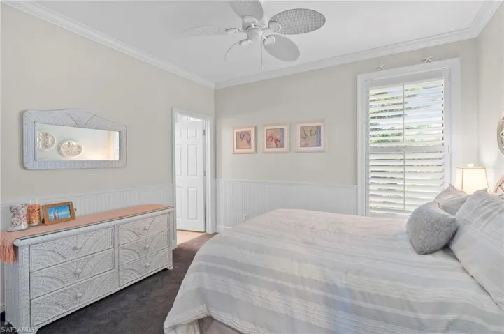 Carpeted bedroom with ornamental molding and ceiling fan