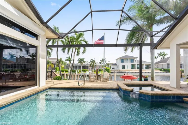 View of pool featuring a water view, glass enclosure, an in ground hot tub, and a patio area