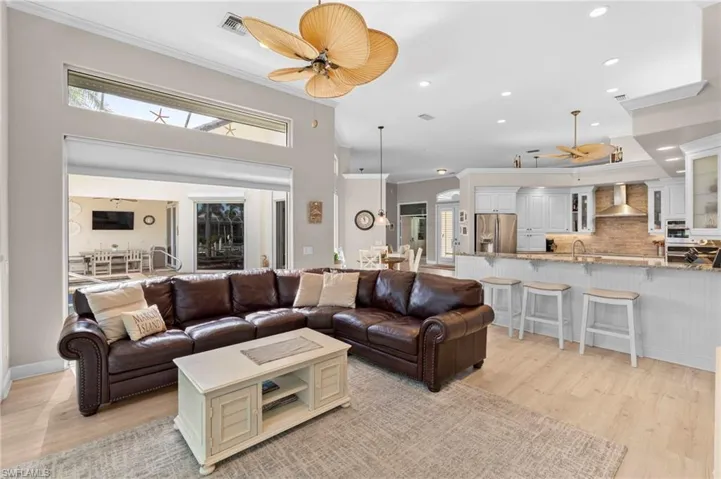 Living room with ceiling fan, light wood-type flooring, and sink