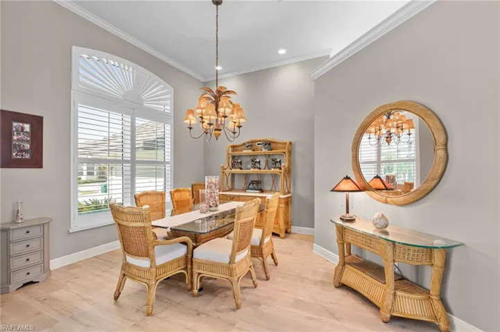 Dining room with a notable chandelier, light wood-type flooring, plenty of natural light, and crown molding