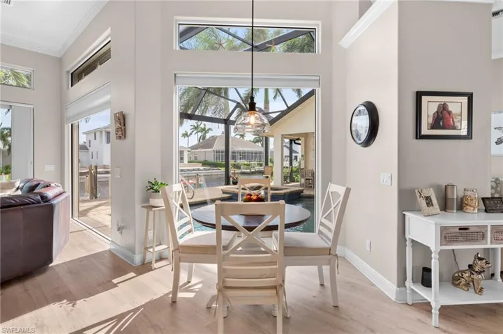 Dining room featuring light hardwood / wood-style flooring, a towering ceiling, a chandelier, and ornamental molding