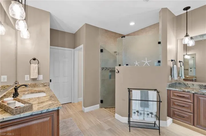 Bathroom with wood-type flooring, a shower with door, and vanity
