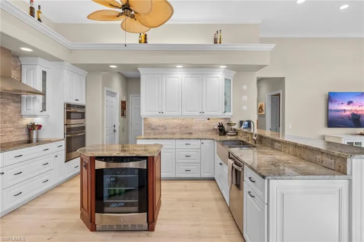 Kitchen featuring wine cooler, sink, white cabinets, kitchen peninsula, and ceiling fan