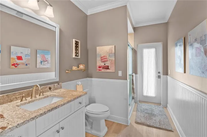 Bathroom featuring walk in shower, hardwood / wood-style floors, crown molding, vanity, and toilet