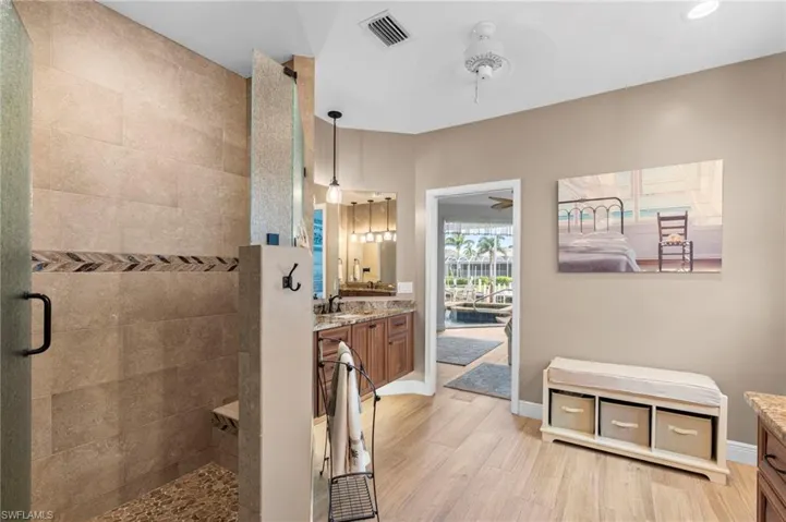 Bathroom with wood-type flooring, ceiling fan, an enclosed shower, and vanity