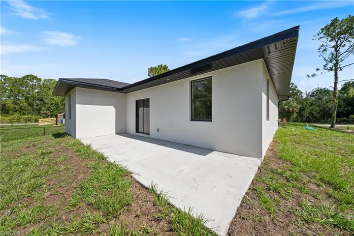 Rear view of property with stucco siding, a patio, and a yard