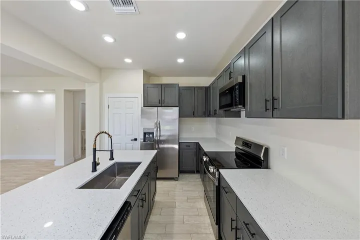 Kitchen featuring stainless steel appliances, light stone countertops, recessed lighting, and light wood finished floors