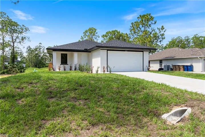 View of front of property with concrete driveway, an attached garage, stucco siding, and a front lawn