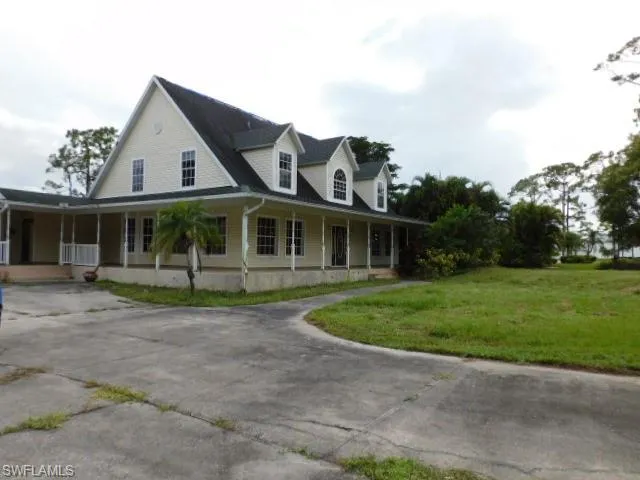 Farmhouse inspired home with a large porch, a front yard, and driveway