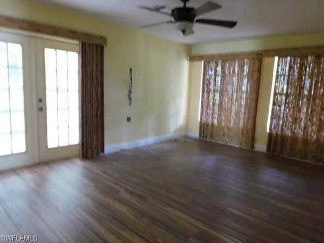 Unfurnished living room with french doors, dark wood-style floors, plenty of natural light, and a ceiling fan