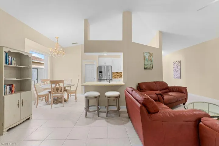 Vaulted ceilings, tiled flooring, open-concept kitchen with breakfast bar, stainless steel appliances, and built-in cabinetry