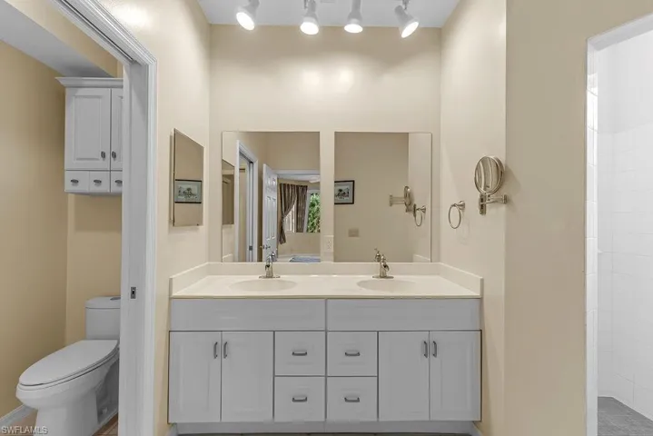 Dual vanity with white cabinetry, brushed nickel hardware, and individual framed mirrors