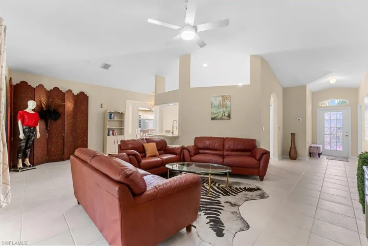 Vaulted ceilings, tiled flooring, ceiling fan, arched doorway, and built-in shelving