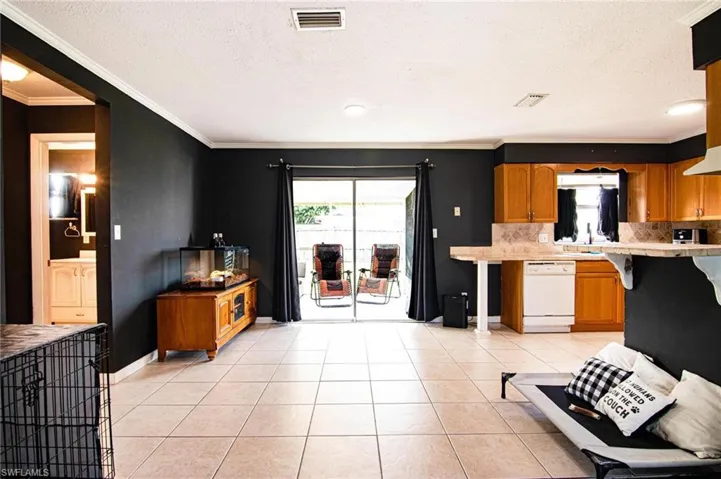 Kitchen with brown cabinets, decorative backsplash, a textured ceiling, healthy amount of natural light, and light tile patterned flooring