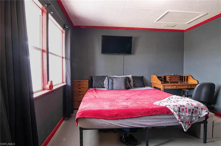 Bedroom with attic access and concrete floors