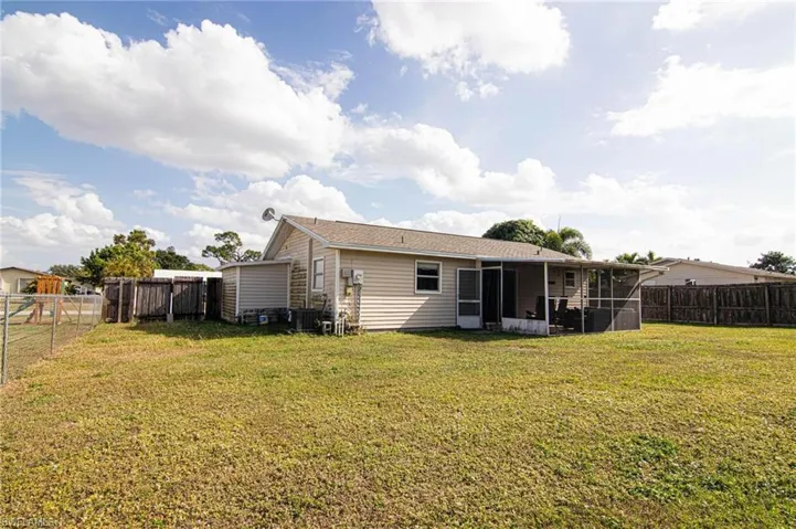Rear view of house with a fenced backyard and a sunroom