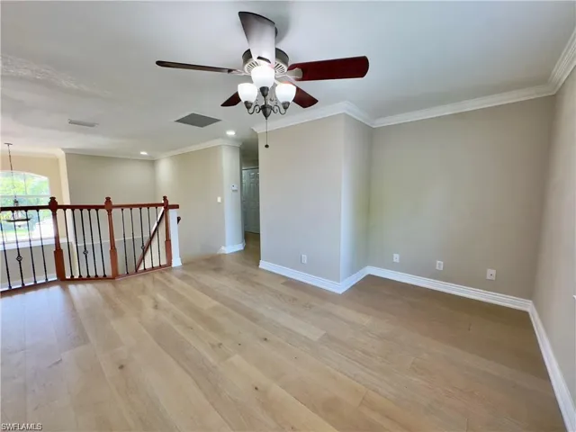 Light wood-finish flooring with crown molding and baseboards
