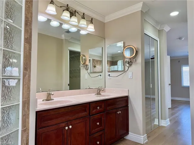 Double vanity with a light-toned countertop, wood-finish cabinetry, and brushed nickel fixtures