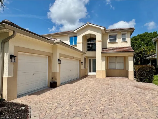 Stucco exterior residence featuring a tile roof and extensive paver driveway