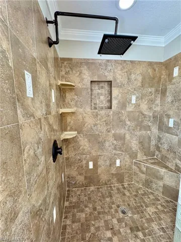 Walk-in shower featuring extensive tiled surrounds, a built-in corner bench, and a rain showerhead with industrial-style plumbing