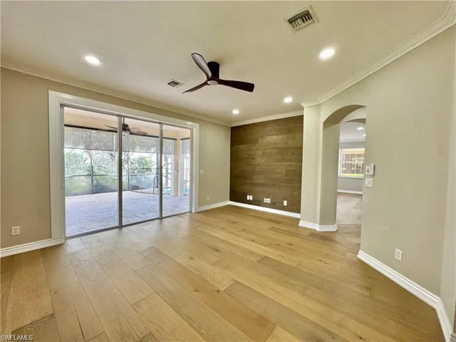Spacious interior room featuring wood-finish flooring, a wood-paneled accent wall, and recessed ceiling lighting