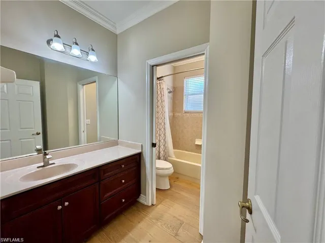Bathroom featuring a vanity with an integrated sink, a large wall-mounted mirror, brushed nickel light fixture, and crown molding