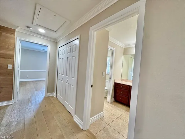 Hallway featuring wood-finish flooring, recessed lighting, crown molding, and a utility access panel