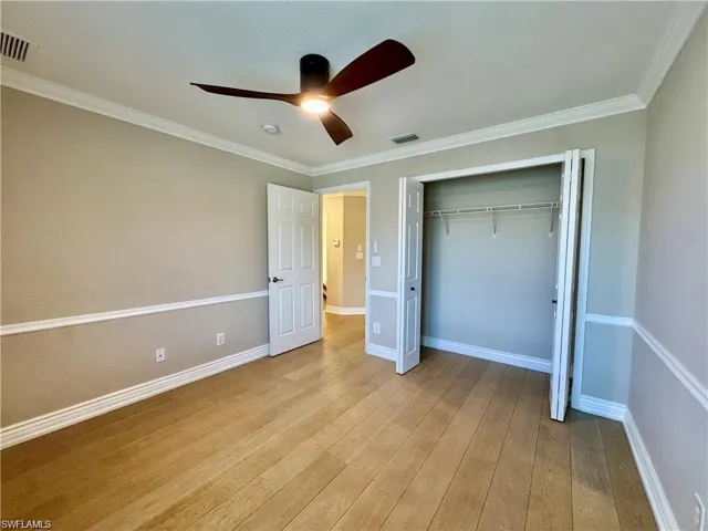 Spacious room featuring wood-finish flooring, a contemporary ceiling fan with integrated lighting, and a closet with bifold doors