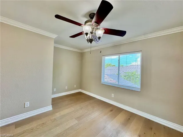 Room featuring wood-finish flooring, crown molding, and baseboards