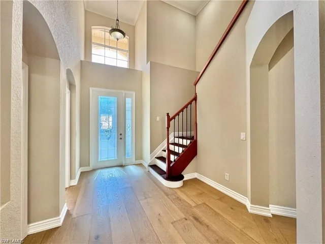 Vaulted foyer with a decorative glass entry door, side light, and transom window