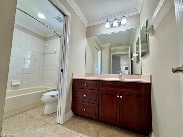 Bathroom featuring a wood-finish vanity with a light-toned countertop, a large mirror, and a three-light fixture