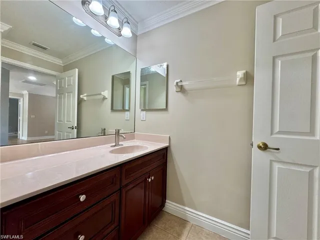 Bathroom vanity featuring a light-toned countertop, an integrated sink, and a brushed nickel faucet