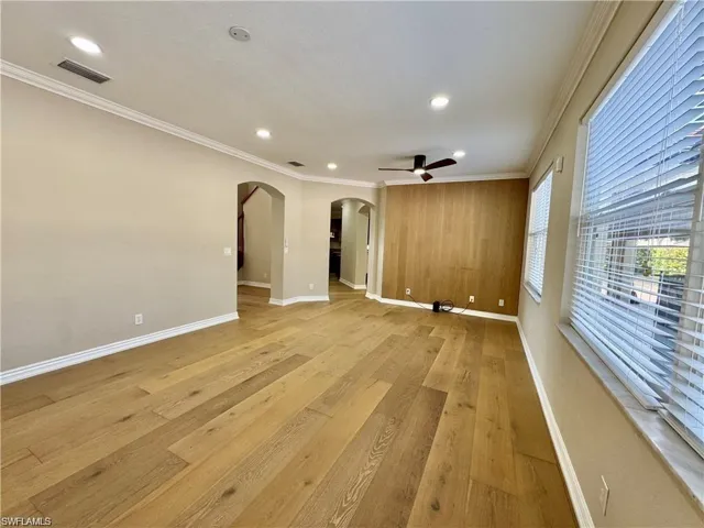 Spacious interior featuring wide-plank wood-finish flooring, a wood-paneled accent wall, recessed lighting, and a ceiling fan