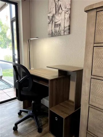 Home office featuring a textured wall and wood finished floors