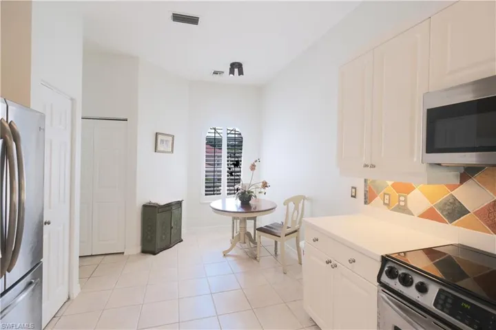 Kitchen featuring stainless steel appliances, white cabinetry, tasteful backsplash, and light tile floors