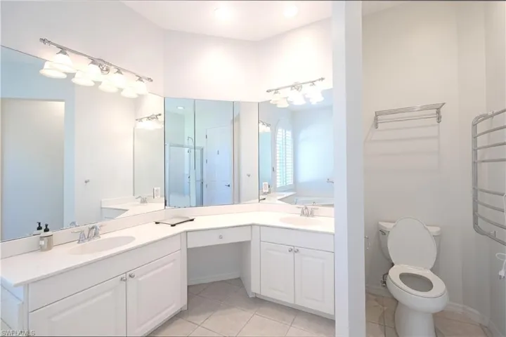 Bathroom with dual bowl vanity, tile flooring, a bathing tub, and toilet