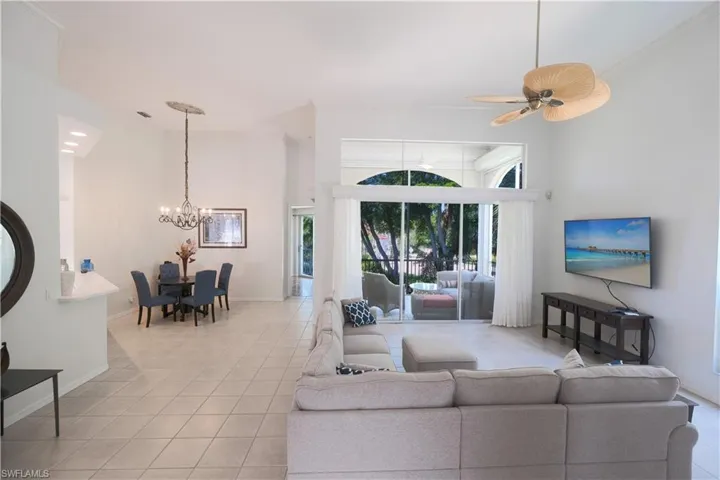 Living room featuring a high ceiling, a healthy amount of sunlight, and light tile floors