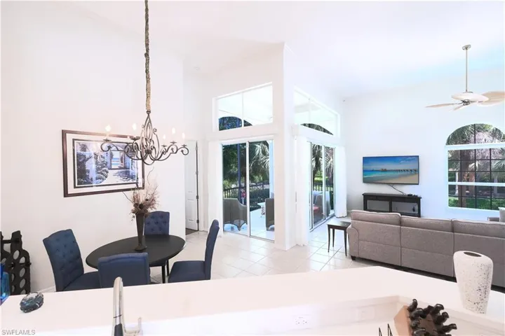 Tiled dining space featuring a towering ceiling, a wealth of natural light, and ceiling fan with notable chandelier