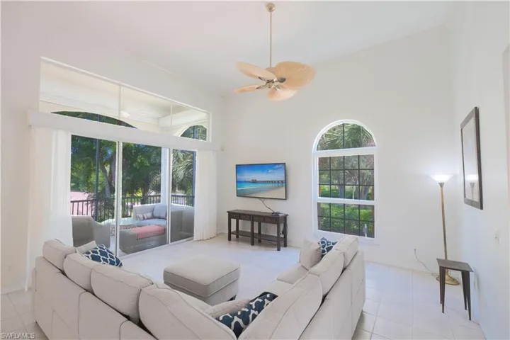 Living room with a towering ceiling, ceiling fan, and tile floors