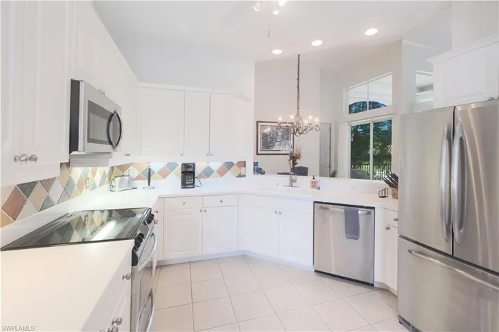 Kitchen featuring white cabinets, tasteful backsplash, light tile flooring, and stainless steel appliances