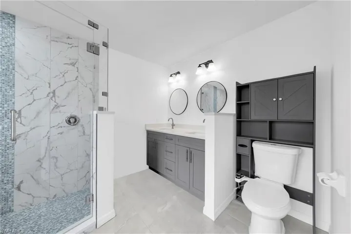 Bathroom with a marble finish shower and double vanity