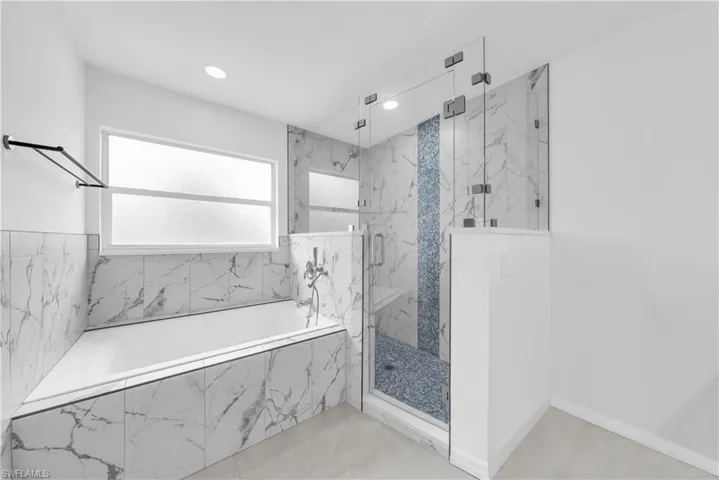 Bathroom featuring a bath, a marble finish shower, and recessed lighting