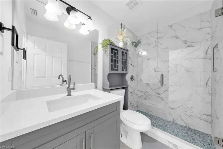 Full bathroom with vanity and a marble finish shower