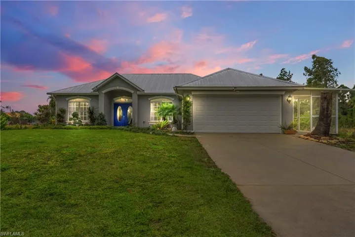 Ranch-style house featuring stucco siding, a front yard, concrete driveway, and a garage
