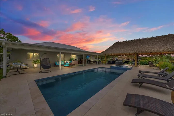 Pool at dusk featuring a patio area, a pool with connected hot tub, and an outdoor living space