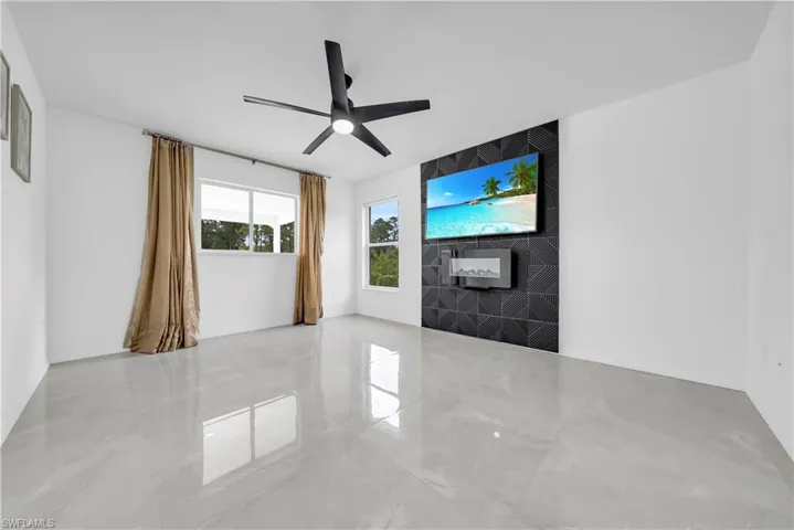 Unfurnished living room featuring marble tiled flooring and ceiling fan